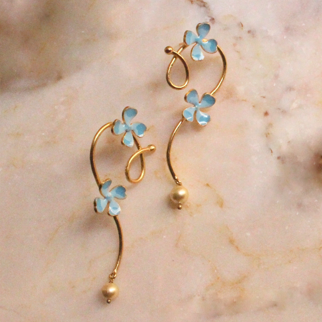 Pair of gold curl earrings adorned with soft blue enamel flowers and small pearl-like drops
