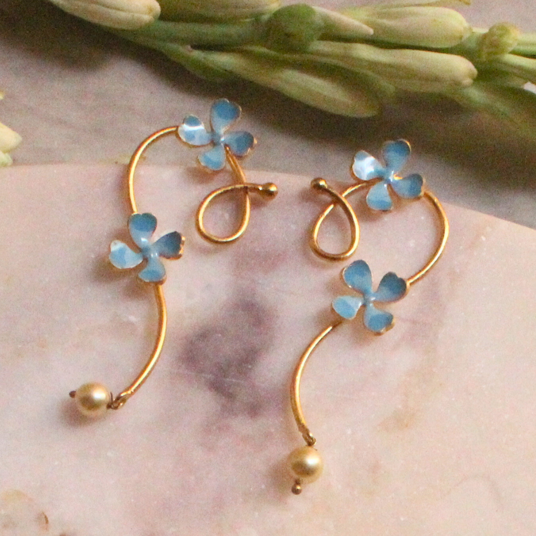 Pair of gold curl earrings adorned with soft blue enamel flowers and small pearl-like drops