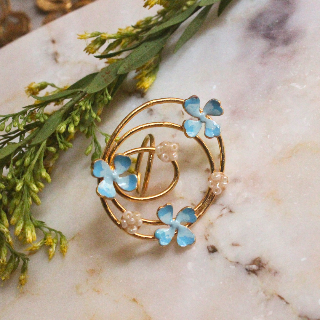 Elegant gold spiral ring with blue enamel flower blossoms and pearl-like accents