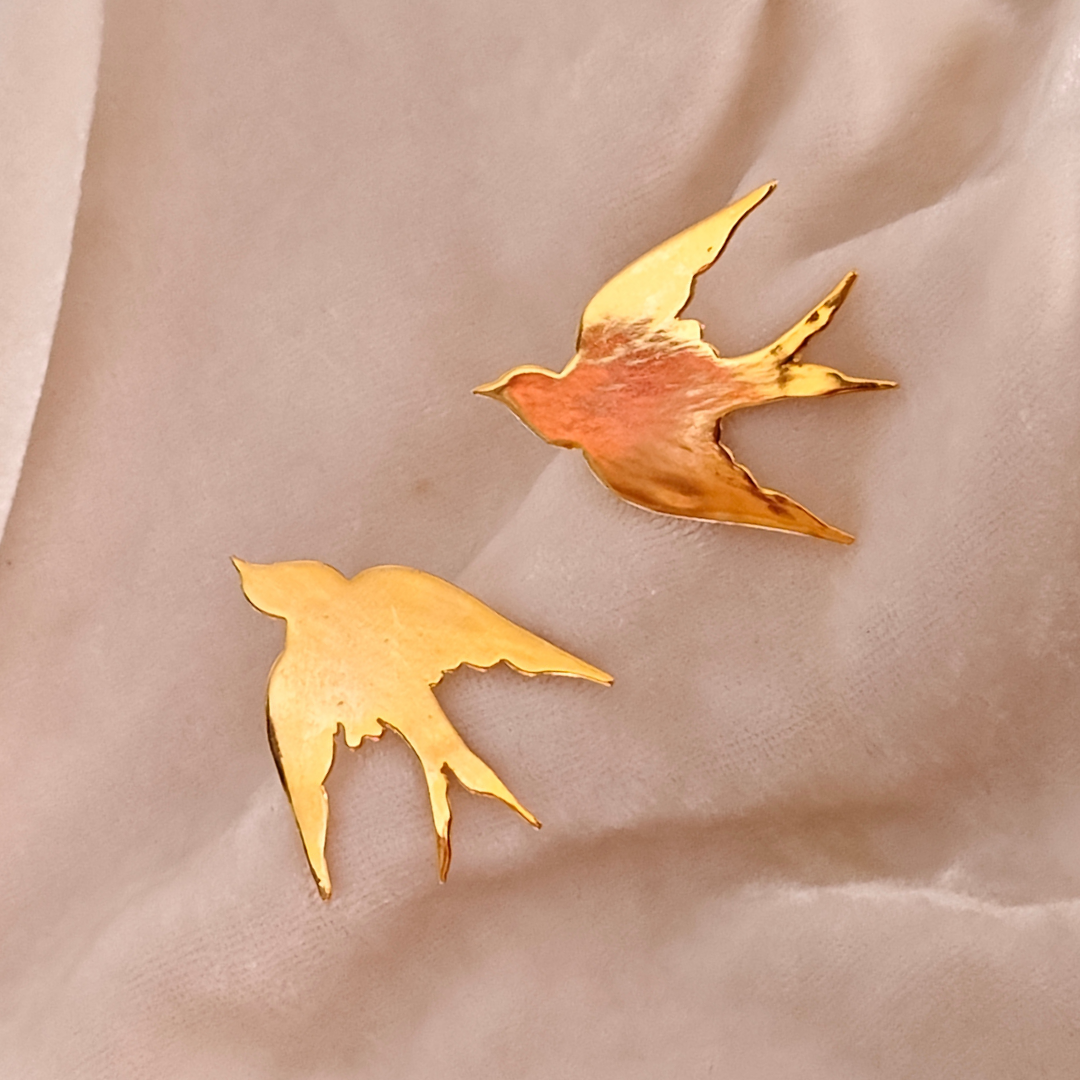 A pair of Gold Plated Flying Bird Earrings featuring elegant bird-in-flight silhouettes crafted from brass with a polished 18k rhodium gold finish.