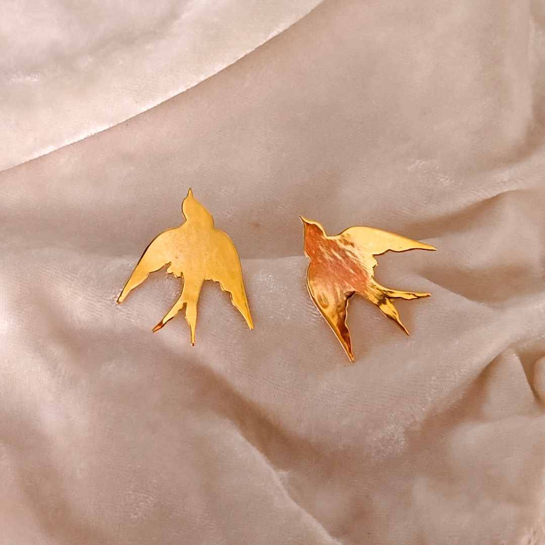 A pair of Gold Plated Flying Bird Earrings featuring elegant bird-in-flight silhouettes crafted from brass with a polished 18k rhodium gold finish.