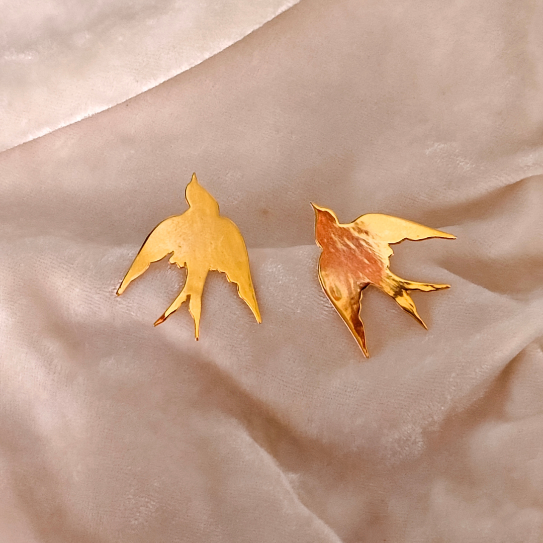 A pair of Gold Plated Flying Bird Earrings featuring elegant bird-in-flight silhouettes crafted from brass with a polished 18k rhodium gold finish.