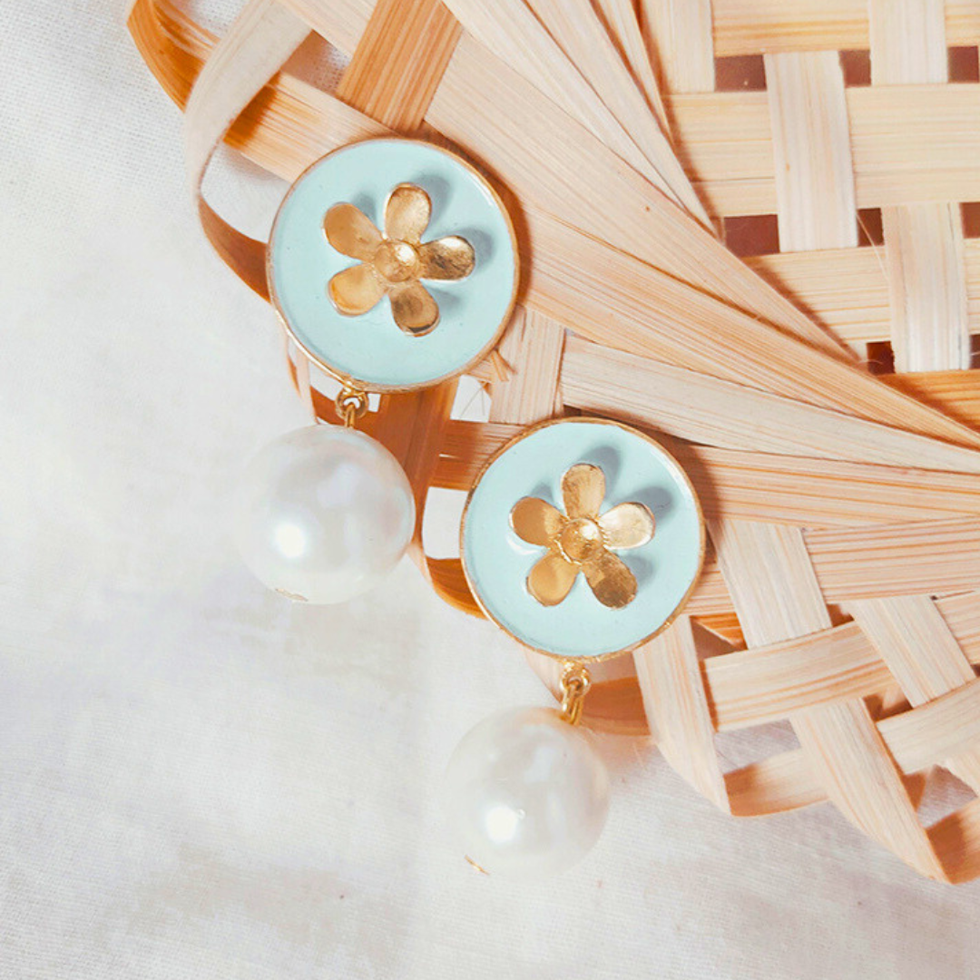 A pair of handcrafted earrings featuring sky blue Meena enamel discs with gold floral motifs and elegant faux pearl drops, set in 18K gold-plated brass.