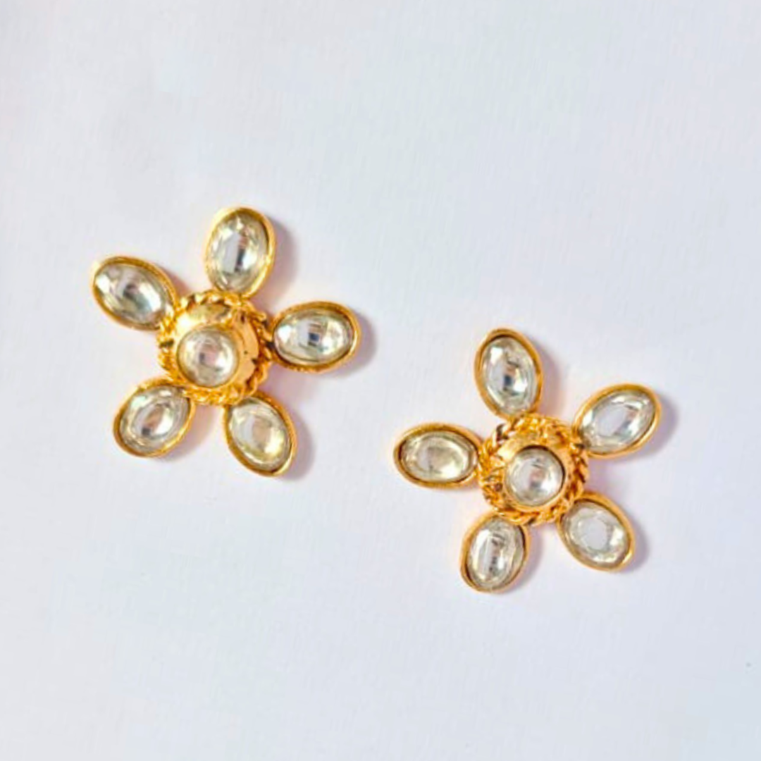 A pair of gold-plated floral stud earrings with six clear faux kundan stones arranged as petals around a central stone