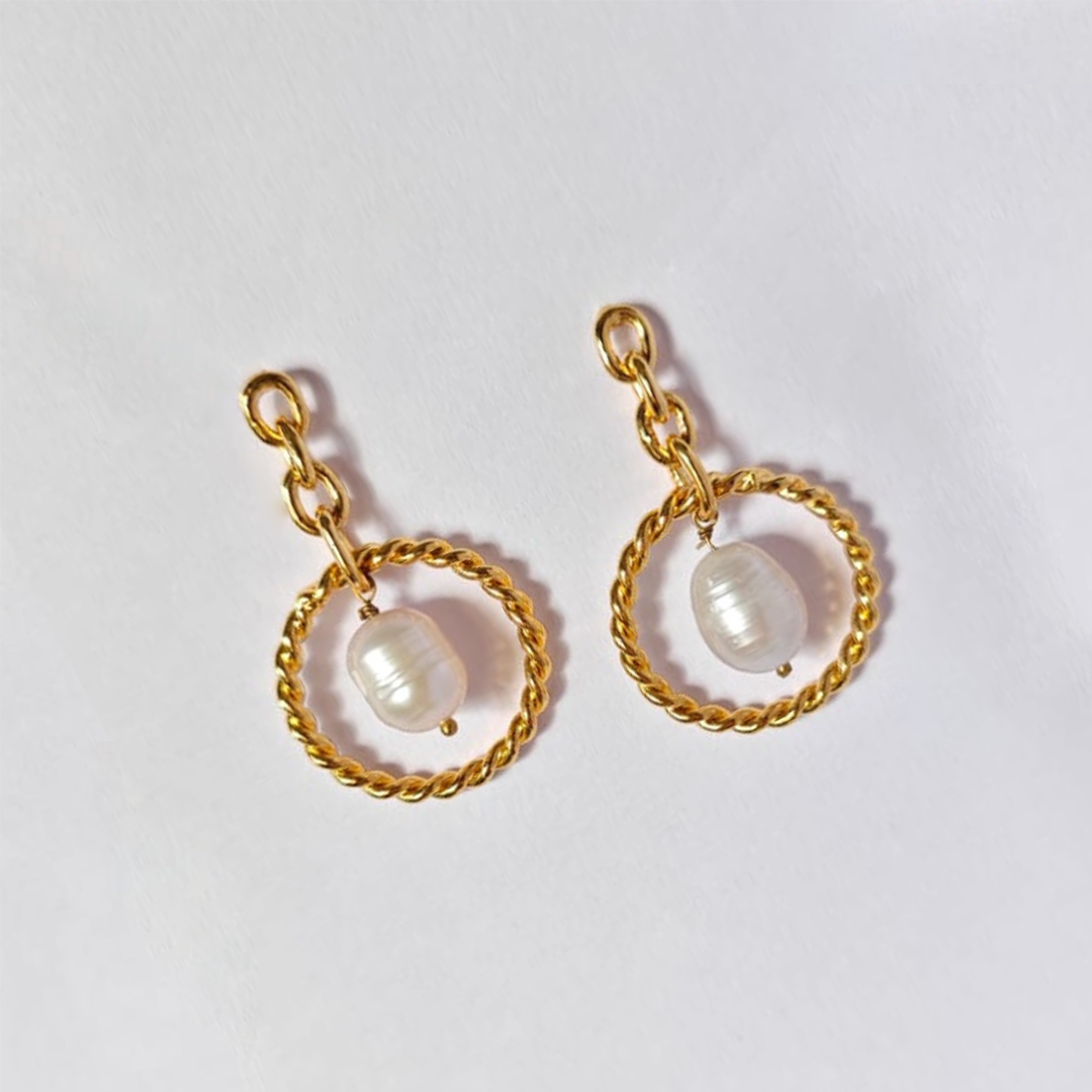 A pair of elegant dangle earrings featuring natural tumble pearl beads suspended in twisted gold-plated circular loops, connected by delicate gold chain links
