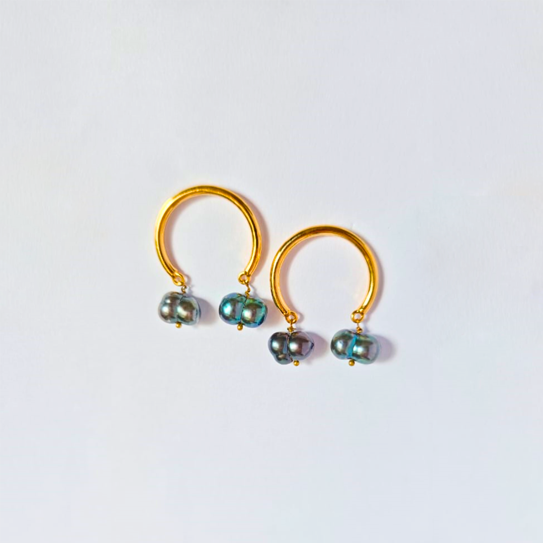 A pair of elegant earrings featuring smooth gold-plated hoops with two iridescent dark baroque pearls suspended from each