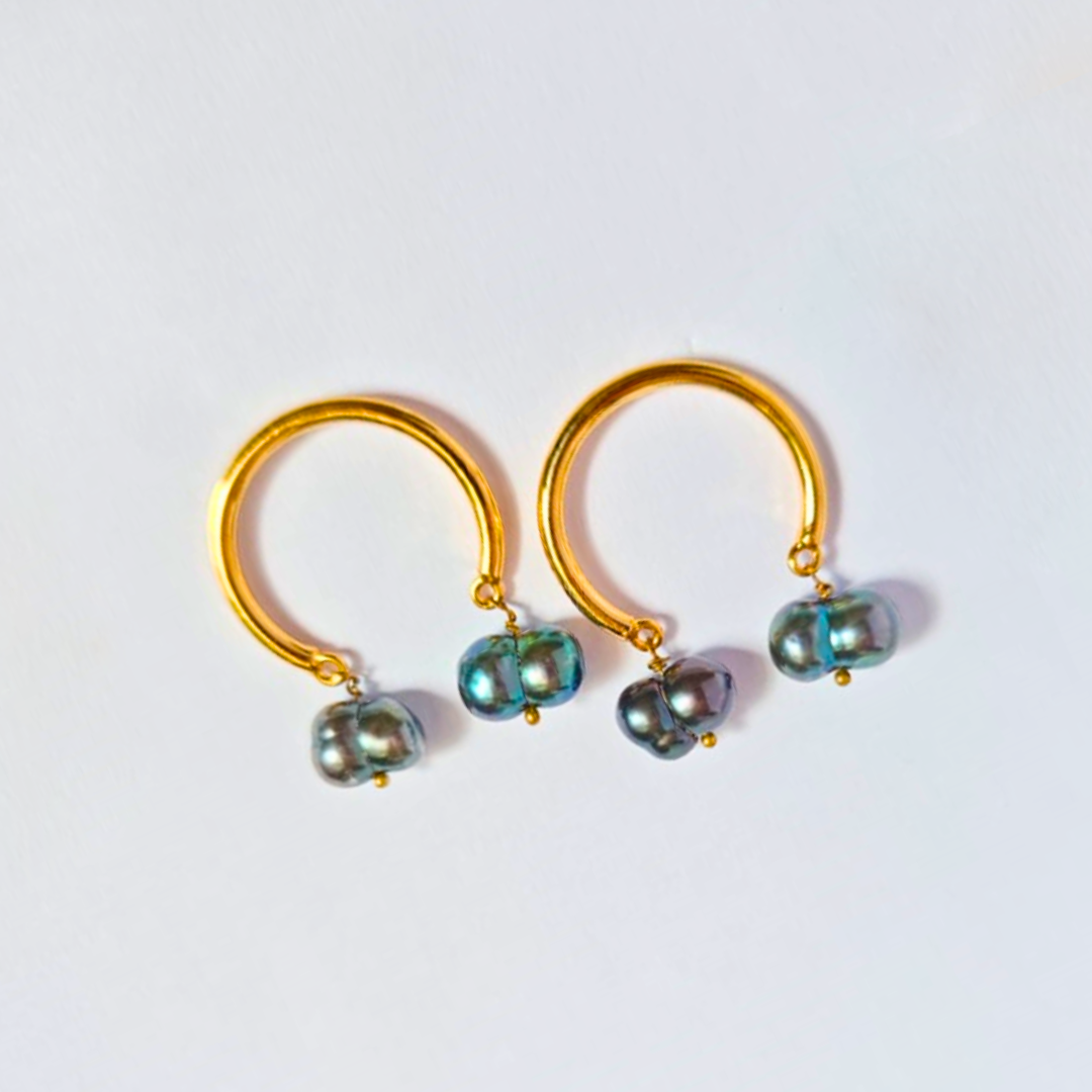 A pair of elegant earrings featuring smooth gold-plated hoops with two iridescent dark baroque pearls suspended from each