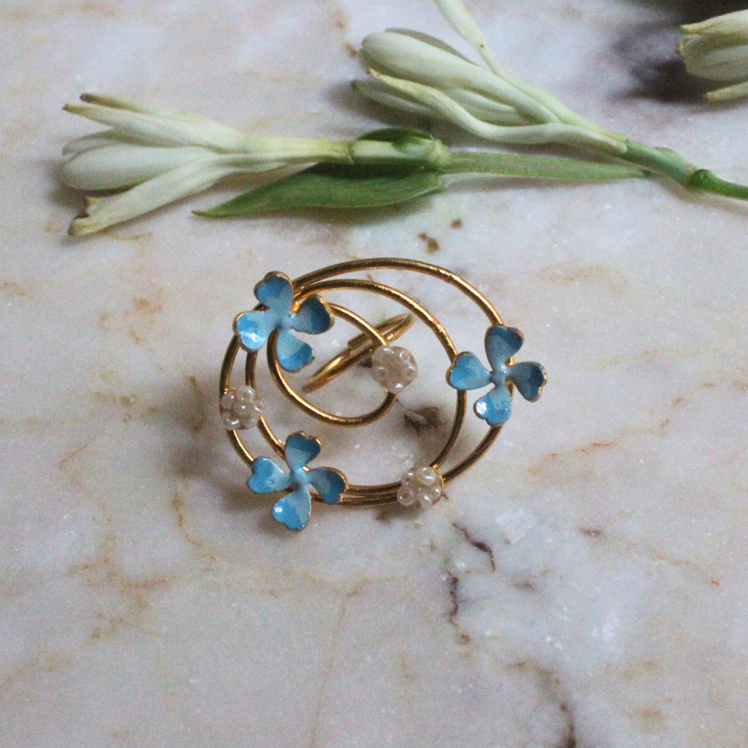 Elegant gold spiral ring with blue enamel flower blossoms and pearl-like accents