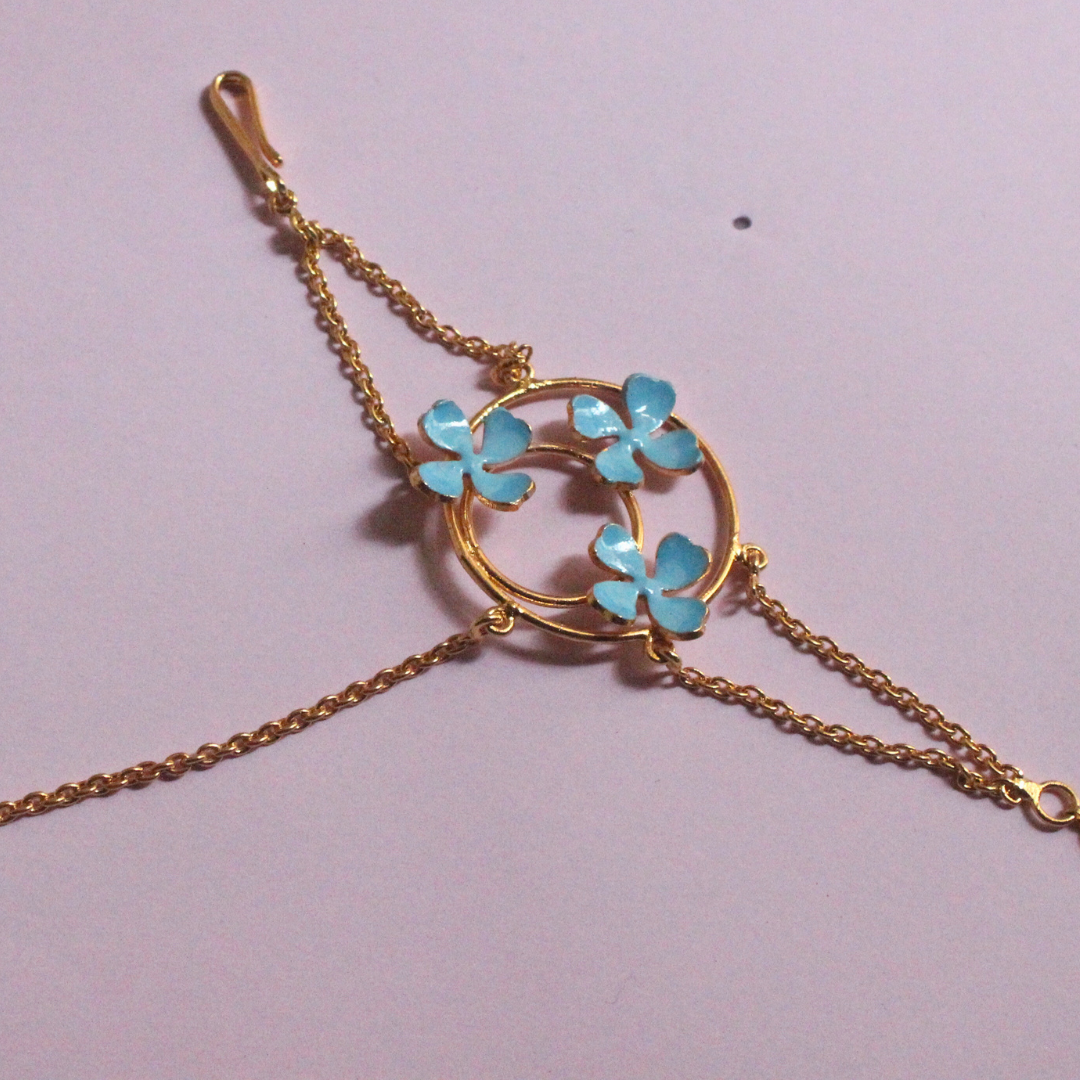 Handmade brass and 18k rhodium gold plated bracelet with fine chains connecting a circular floral motif of blue enamel flowers