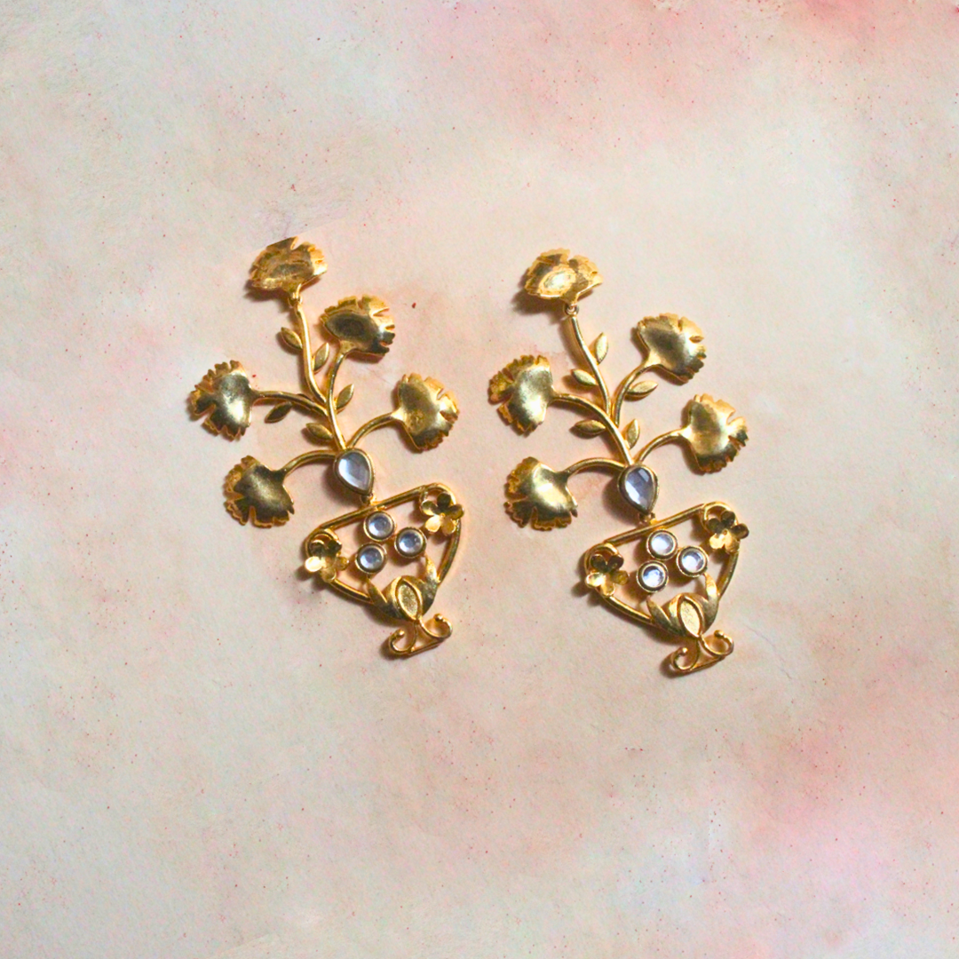 Pair of brass and 18k rhodium gold plated statement earrings with sculptural floral designs emerging from ornate urn-shaped bases, accented with luminous stones