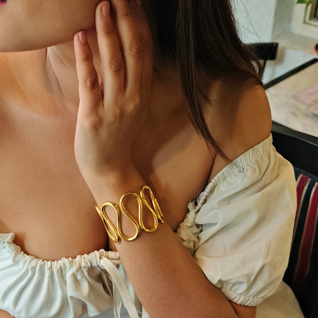 Gold-plated spiral handcuff bangle with wave-like design, crafted from brass