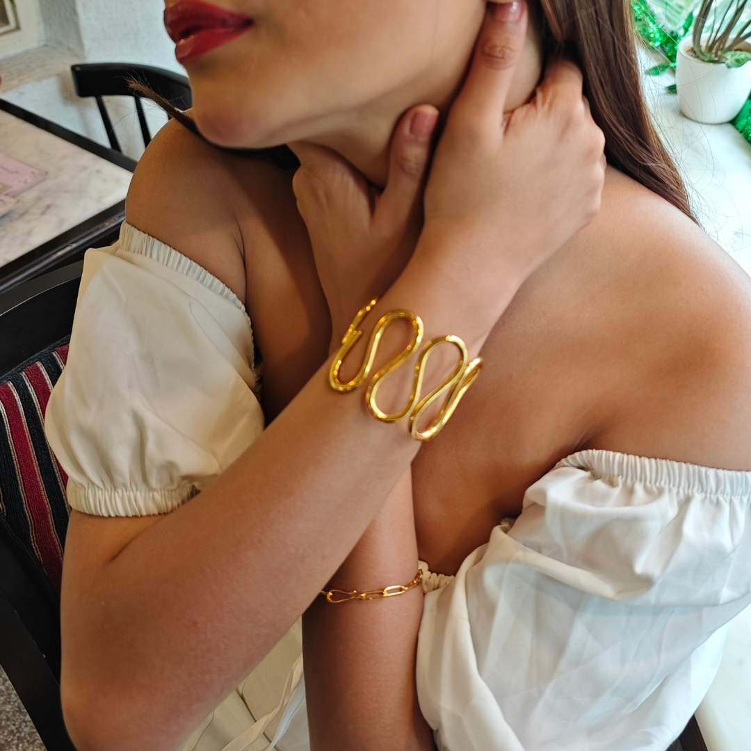 Gold-plated spiral handcuff bangle with wave-like design, crafted from brass