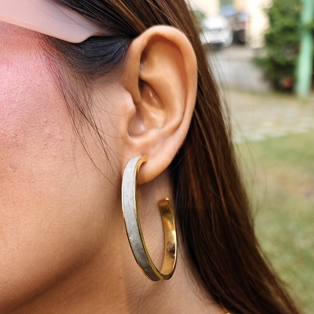 Large hoop earring made of gold-plated brass with a matte cement inlay, combining smooth texture and metallic shine.