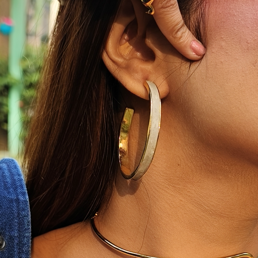 Large hoop earring made of gold-plated brass with a matte cement inlay, combining smooth texture and metallic shine.