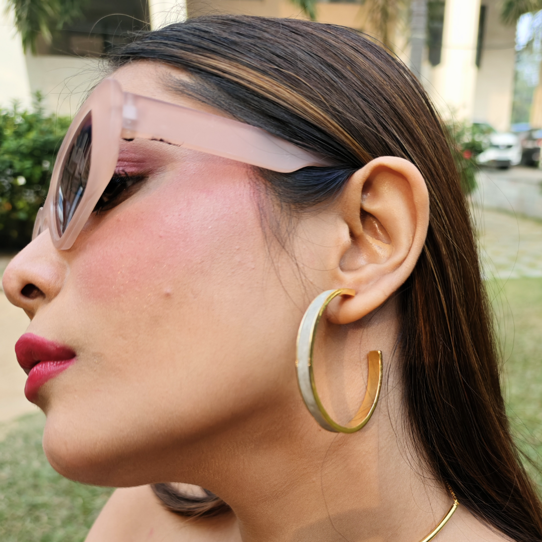 Large hoop earring made of gold-plated brass with a matte cement inlay, combining smooth texture and metallic shine.