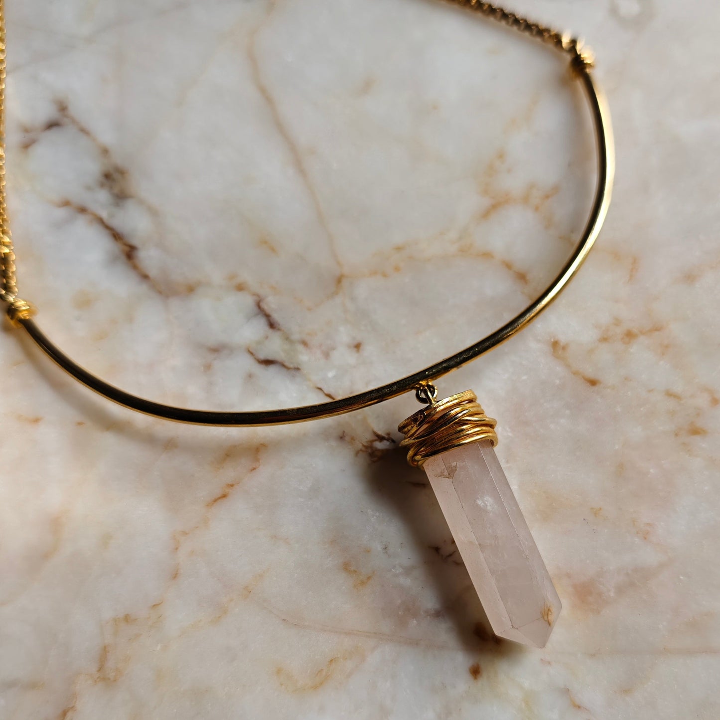 Necklace with a clear stone pendant on a marble surface
