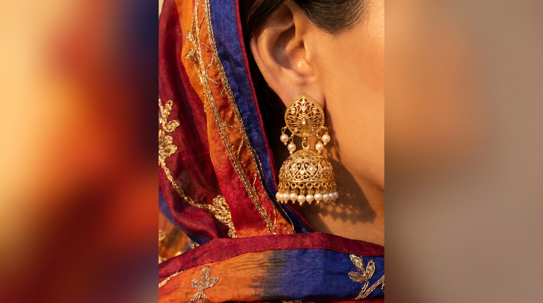 Traditional gold jhumka earrings with filigree and pearl drops against silk dupatta – KANSYA Jewellery