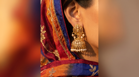 Traditional gold jhumka earrings with filigree and pearl drops against silk dupatta – KANSYA Jewellery