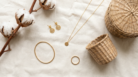 Curated capsule jewellery collection of gold studs, necklace, bangle and ring on cream linen – KANSYA Jewellery