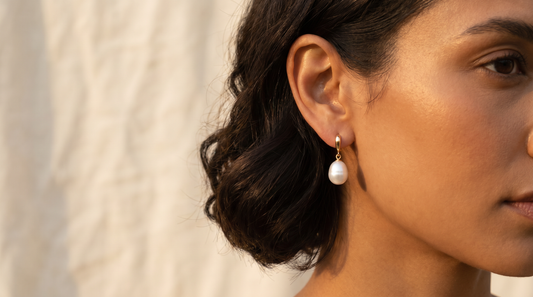 White freshwater pearl drop earrings on a woman's ear, warm elegant light – KANSYA Jewellery