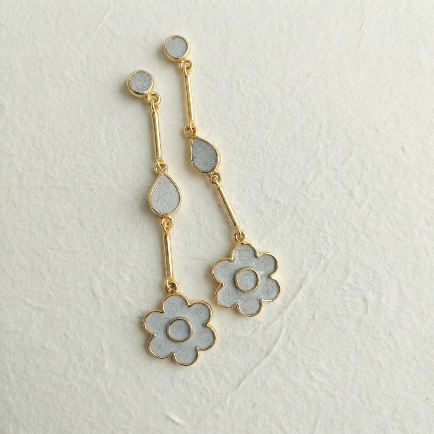 Gold and cement filled flower-shaped earrings on a light gray background