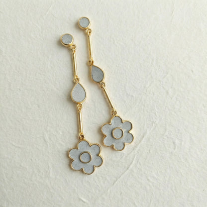 Gold and cement filled flower-shaped earrings on a light gray background