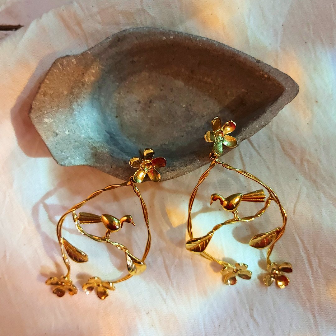 Handcrafted Nature's Embrace dangler earrings with flowers, leaves, and a resting bird, made from brass and 18K rhodium gold