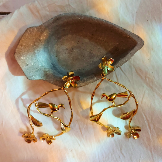 Handcrafted Nature's Embrace dangler earrings with flowers, leaves, and a resting bird, made from brass and 18K rhodium gold