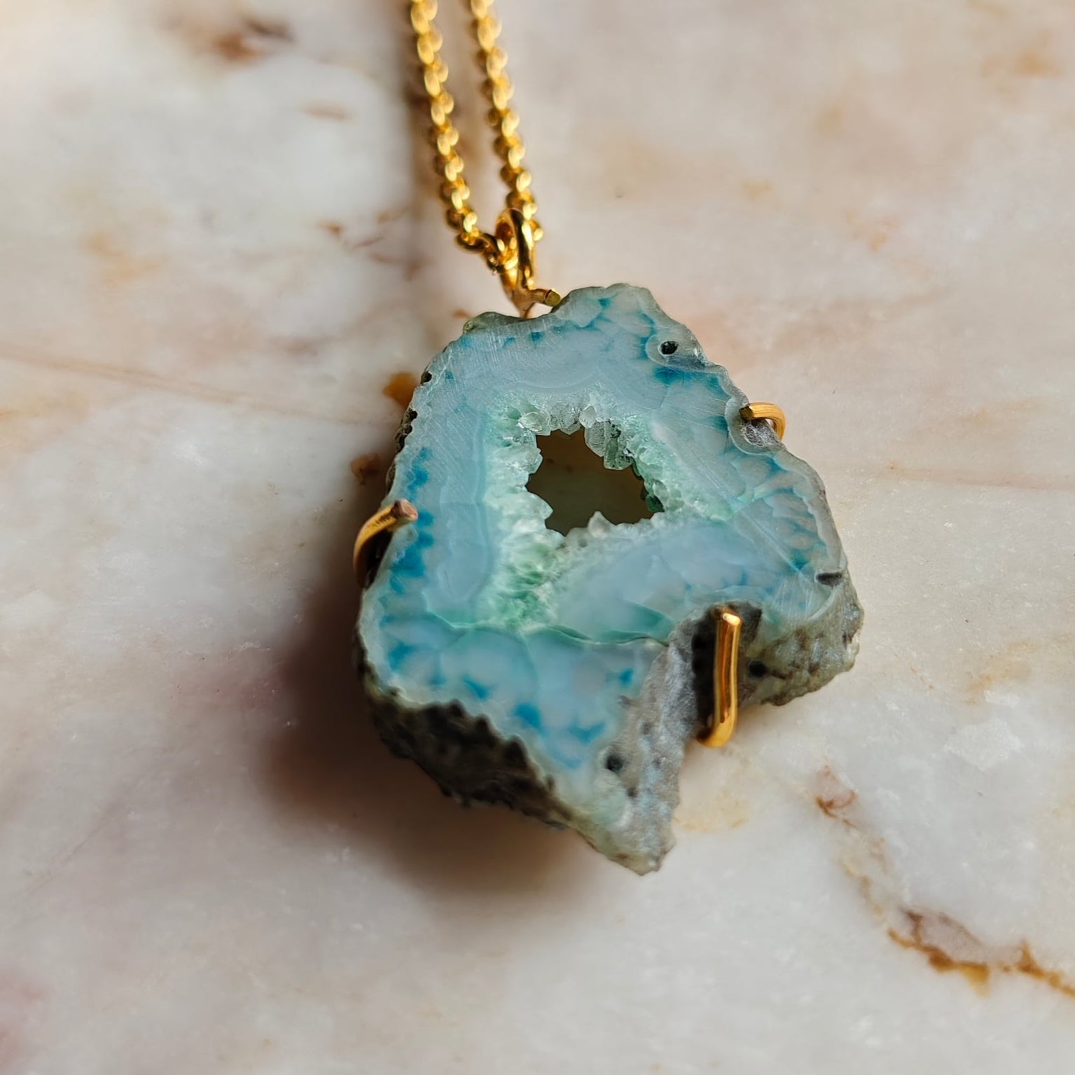 Necklace with a green geode pendant on a marble surface