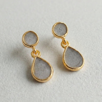 Gold and gray teardrop earrings on a light gray background