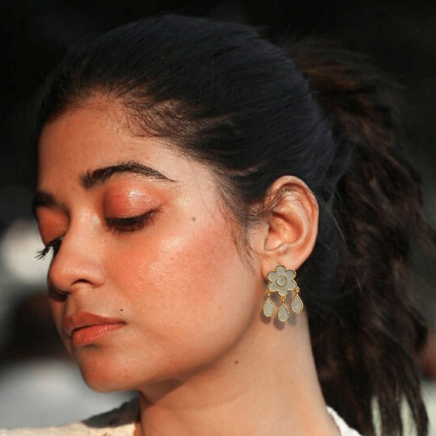 Close-up of a woman wearing a flower shaped cement earring 