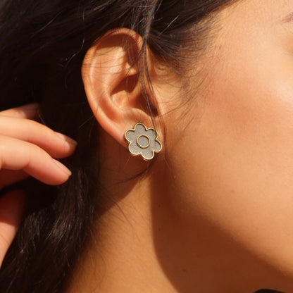Close-up of a person wearing a floral earring with cement filling