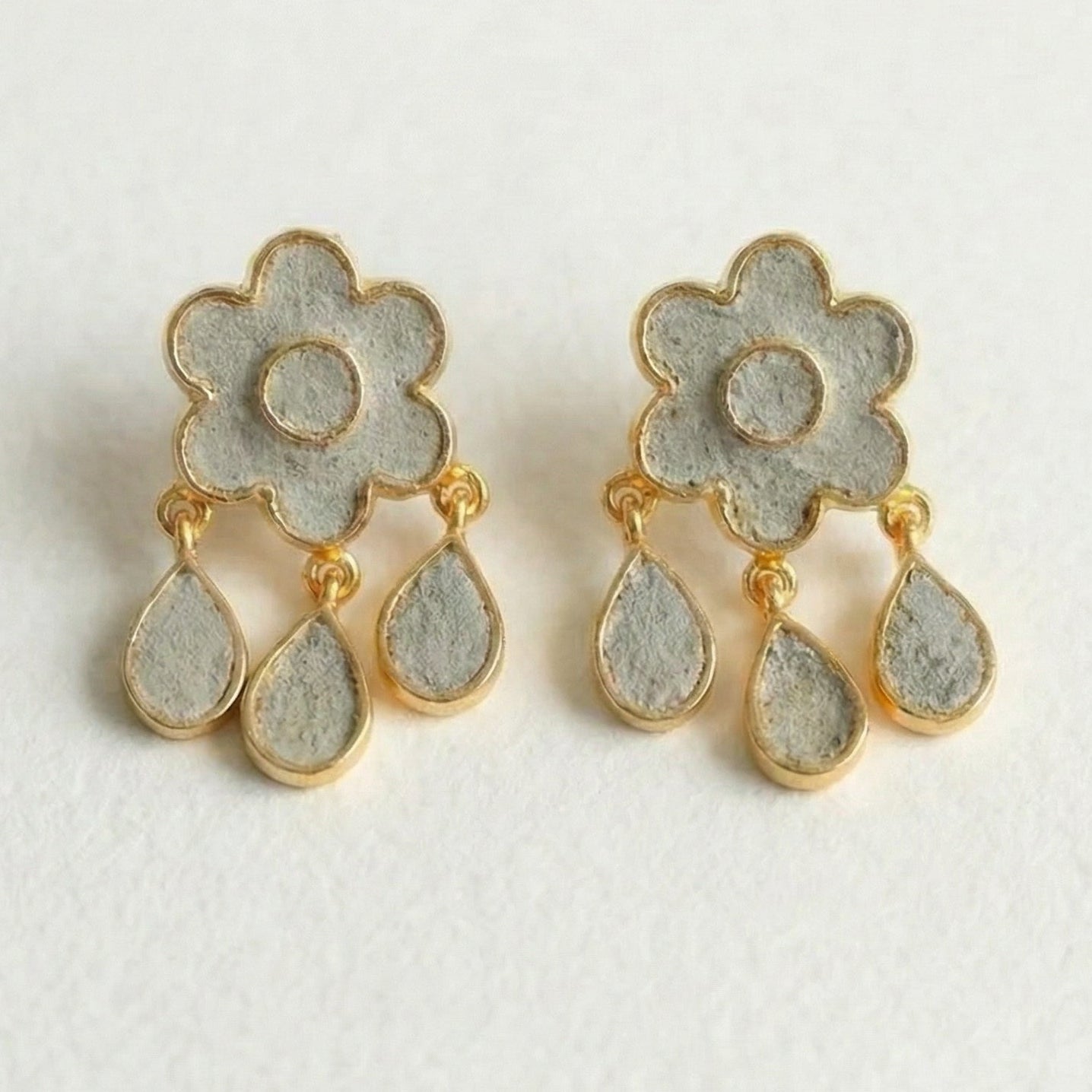 Pair of floral earrings with gold accents on a light gray background