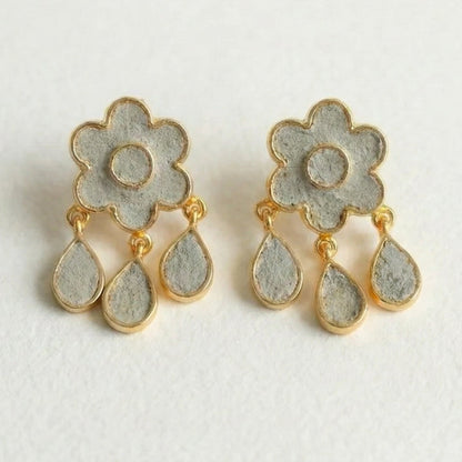 Pair of floral earrings with gold accents on a light gray background