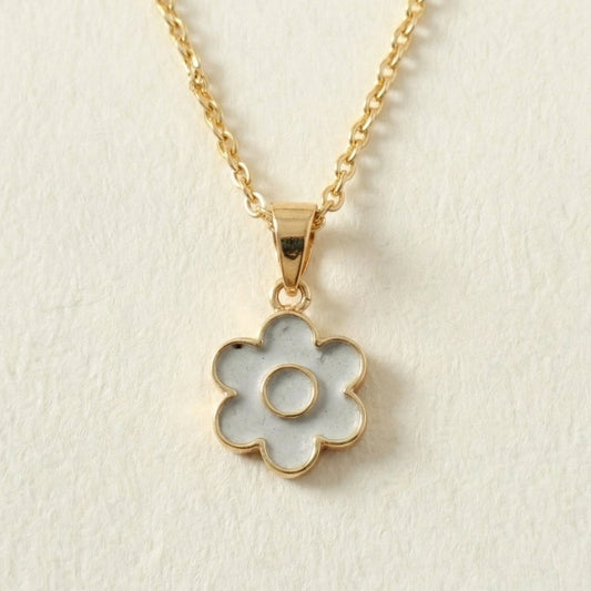 Gold necklace with a flower-shaped cement pendant on a beige background