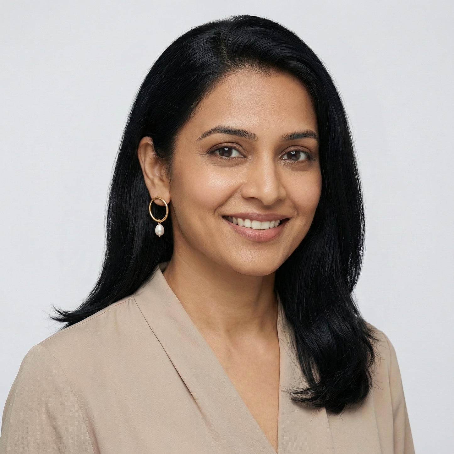 Woman with black hair wearing a round ring with a pearl drop earrings 