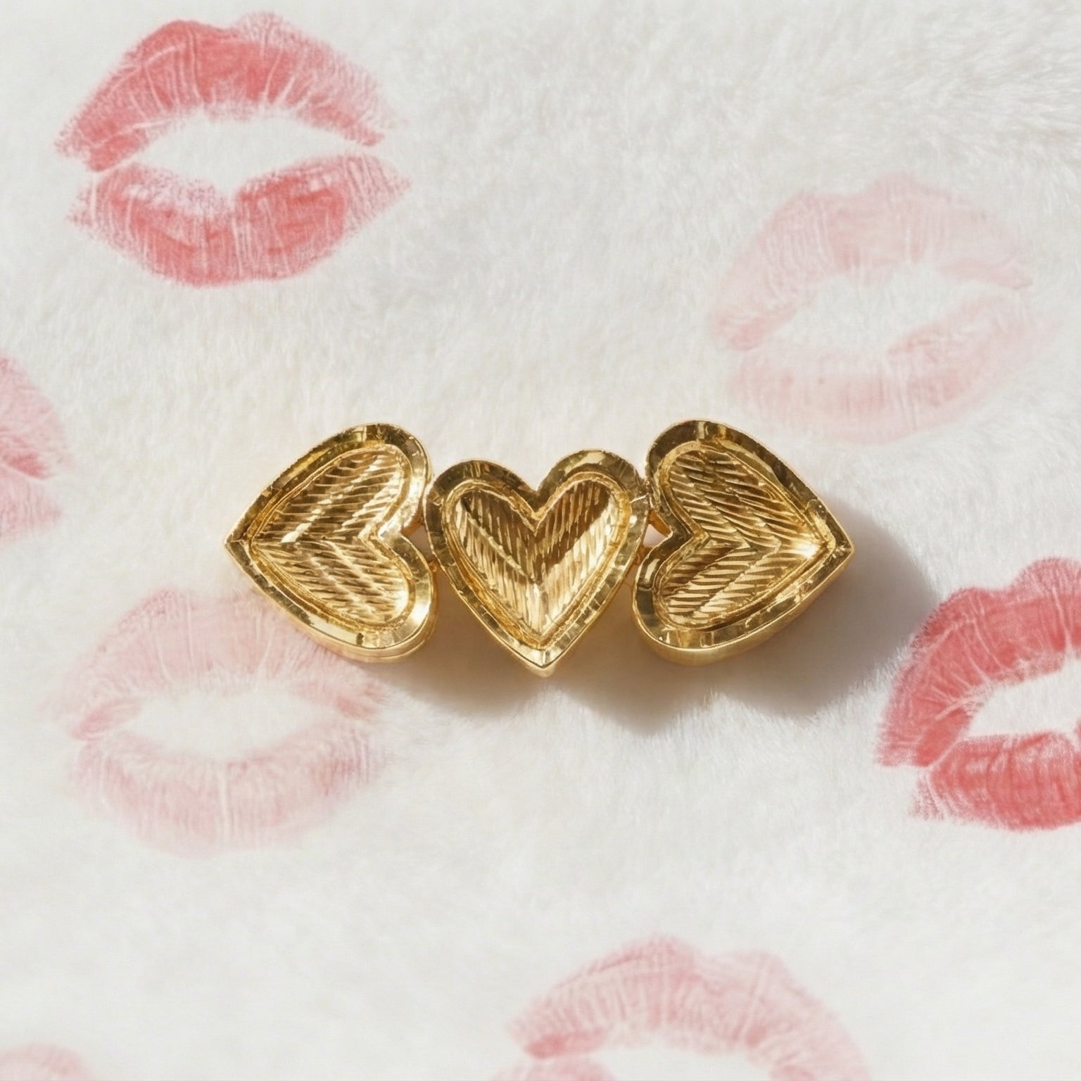 Gold heart-shaped earrings on a white background with pink lipstick marks.