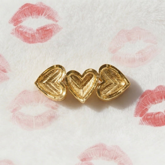 Gold heart-shaped earrings on a white background with pink lipstick marks.