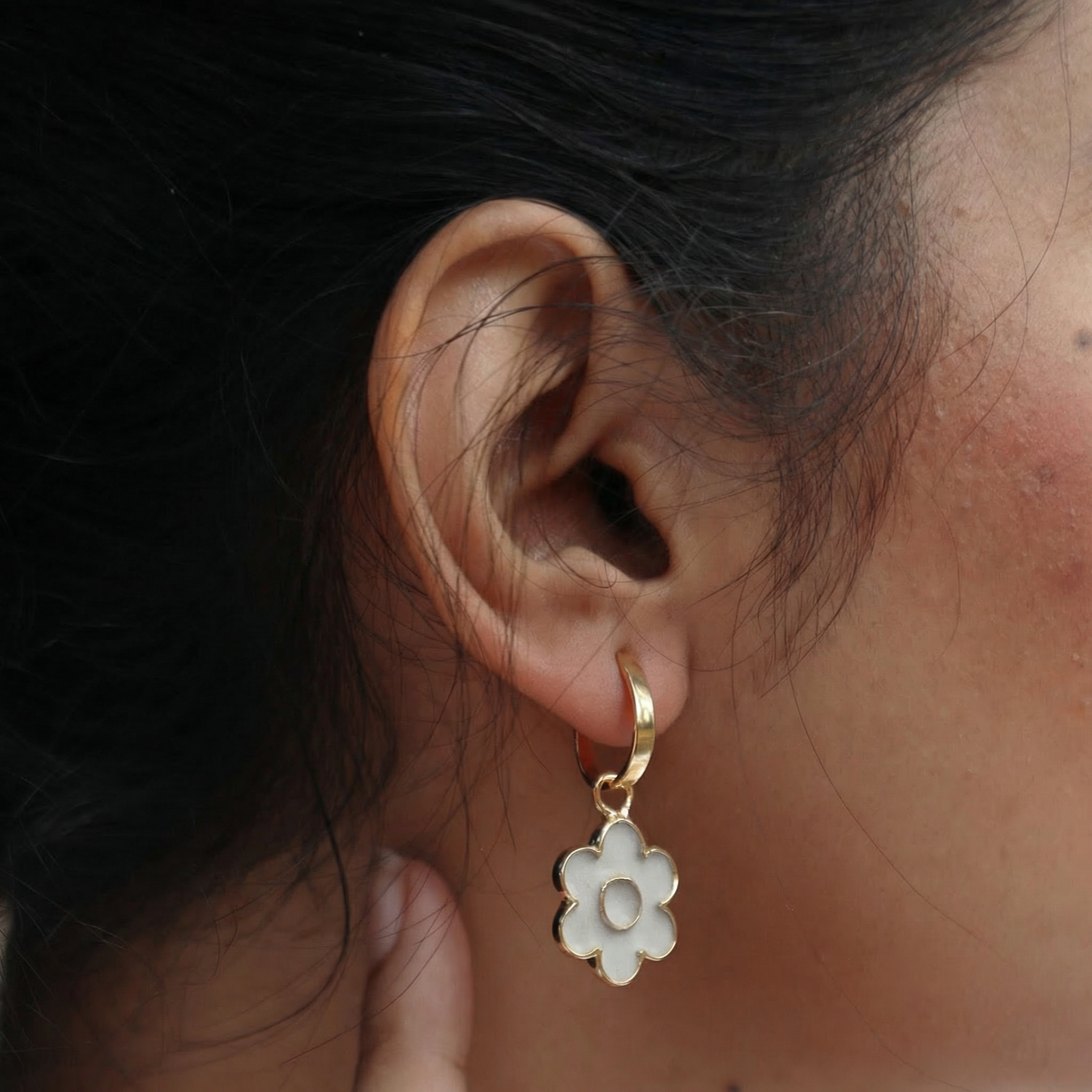 Close-up of an ear wearing a gold earring with a cement detachable flower shape