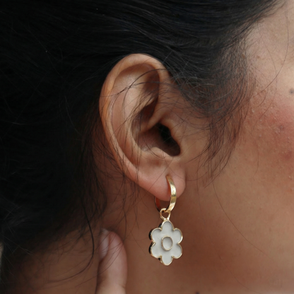 Close-up of an ear wearing a gold earring with a cement detachable flower shape