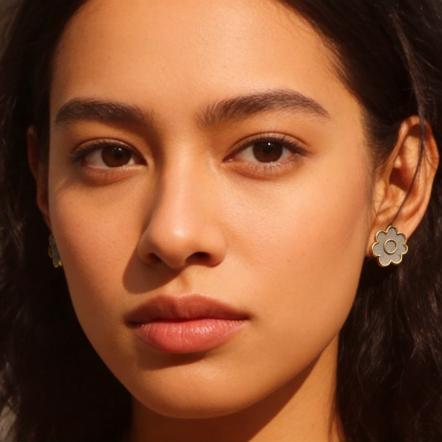 A person wearing flower shaped cement earrings with a warm light.