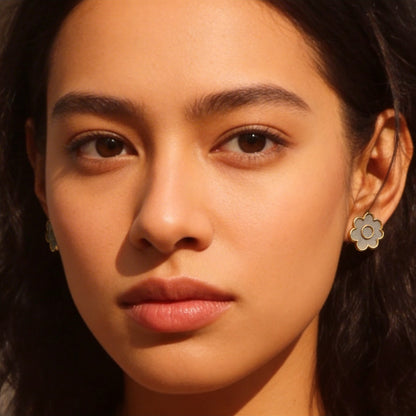 A person wearing flower shaped cement earrings with a warm light.