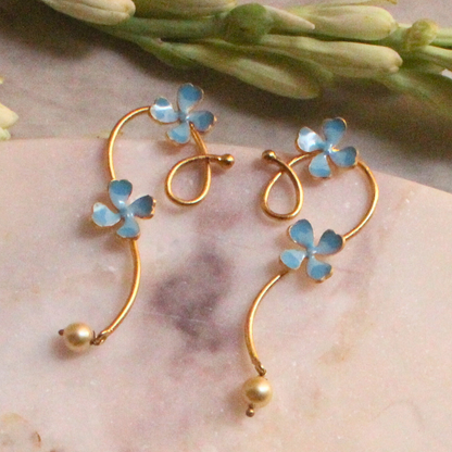 Pair of gold curl earrings adorned with soft blue enamel flowers and small pearl-like drops