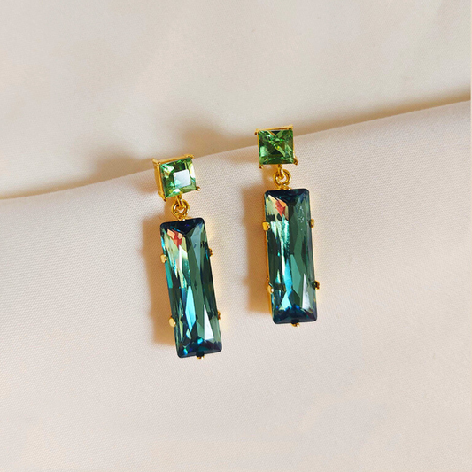 A pair of elegant Avocado Swarovski Earrings featuring square-cut green Swarovski stones and set in 18k rhodium gold-plated brass.
