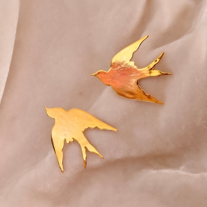 A pair of Gold Plated Flying Bird Earrings featuring elegant bird-in-flight silhouettes crafted from brass with a polished 18k rhodium gold finish.








