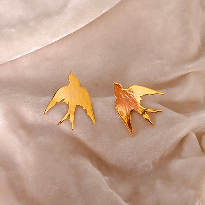 A pair of Gold Plated Flying Bird Earrings featuring elegant bird-in-flight silhouettes crafted from brass with a polished 18k rhodium gold finish.








