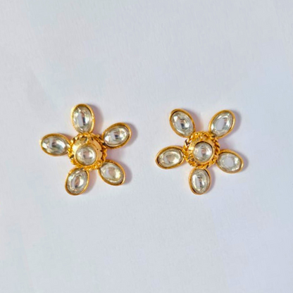 A pair of gold-plated floral stud earrings with six clear faux kundan stones arranged as petals around a central stone