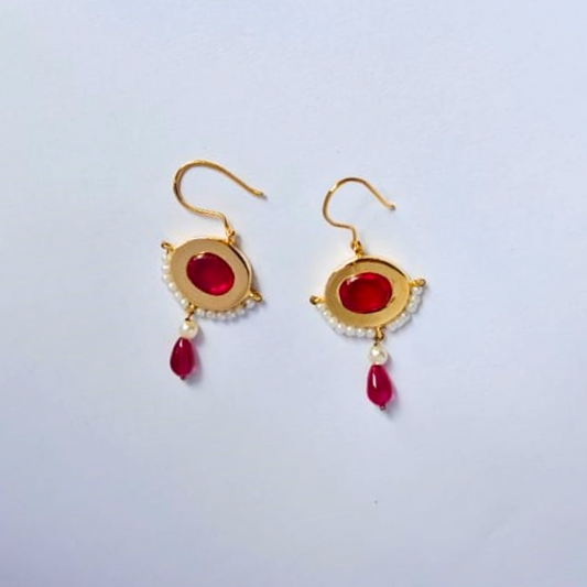 Pair of gold-plated drop earrings featuring bold red oval stones at the center, bordered with tiny white pearls and finished with red and pearl bead dangles