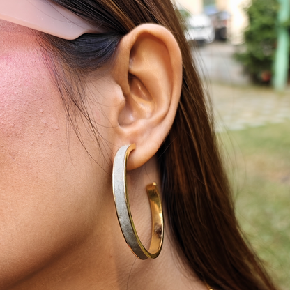 Large hoop earring made of gold-plated brass with a matte cement inlay, combining smooth texture and metallic shine.