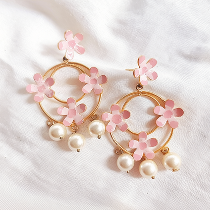 Pair of floral earrings with pink flowers and pearls on a white fabric background